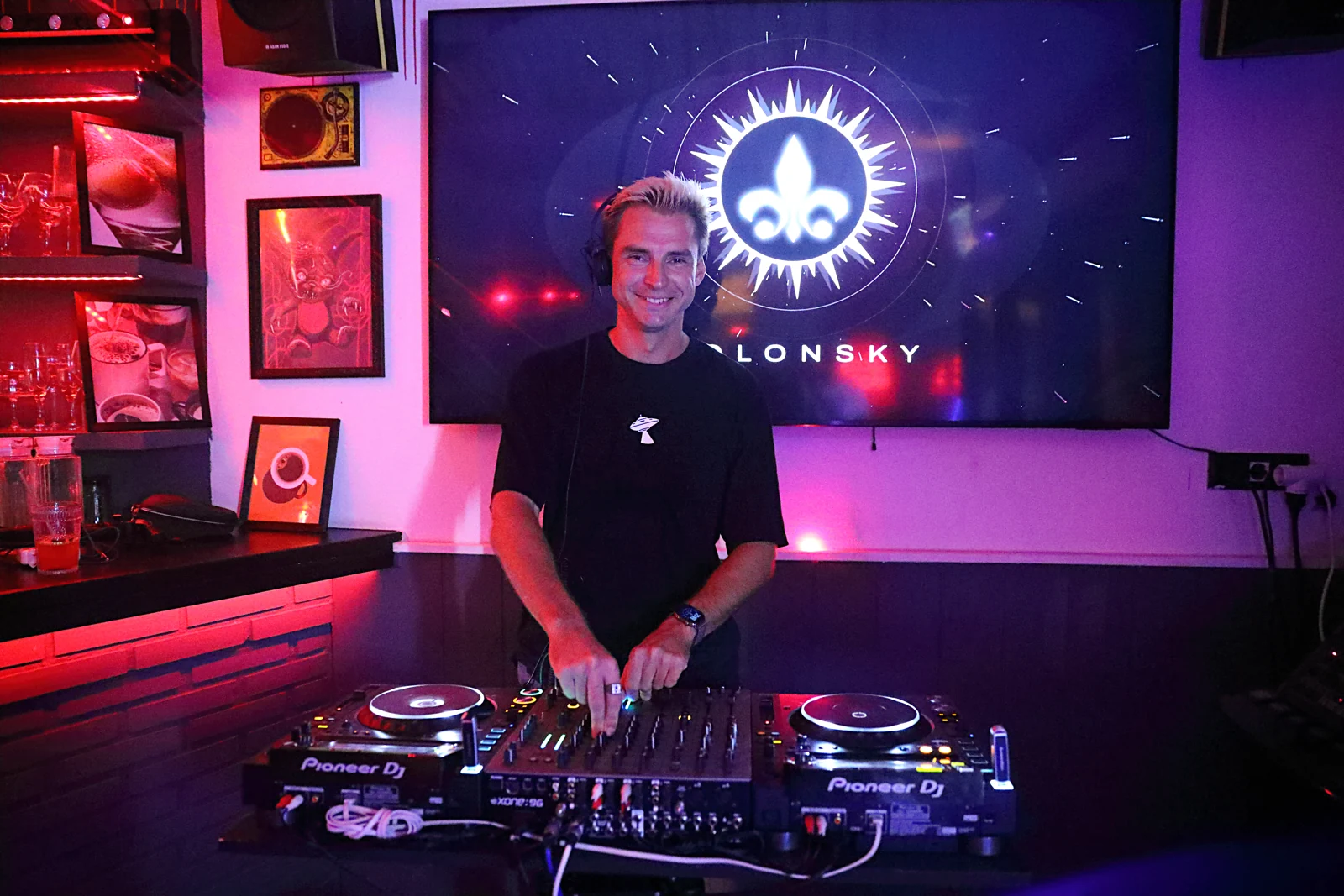 SOLONSKY at the decks with his musical emblem behind him